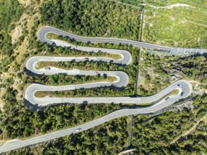 Mountain pass road with multiple hairpins, water pipeline, aerial view, drone shot. Valais,