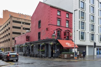 Red building on a street corner with urban flair, cars and a rainy atmosphere, Belfast