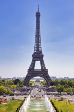 The Eiffel Tower from a central perspective with water fountains and visitors in the foreground,