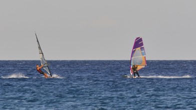 Two windsurfers navigating over the blue sea under clear skies, windsurfing, Meltemi windsurfing