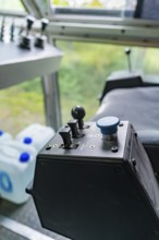 Control unit with a blue button and two levers in front of a window front, Hermann Hesse Bahn track