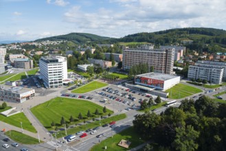 Panorama of the city centre with many cars and surrounding green areas under a blue sky, view from