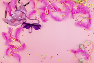 Pink mask, surrounded by feathers, confetti and colourful glasses, vivid pink background, carnival