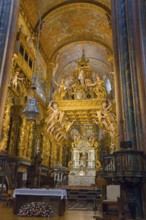 Gold-decorated Baroque church interior with an ornately decorated altar and angels, cathedral,