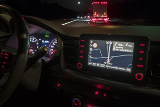 Nocturnal street scene with lorry, fromre an illuminated cockpit with sat nav of a car, Bavaria,