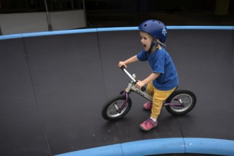 Little girl, 3 years, blonde, helmet, helmet, riding on balance bike, bicycle, skating rink,