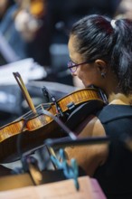 Close-up of a woman playing a violin in the orchestra, concentrated and professional,