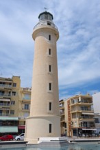 A lighthouse stands out against a clear blue sky, surrounded by buildings, Alexandroupoli,