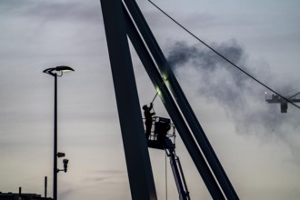 Worker cleans a bridge pier with a high-pressure cleaner on a cherry picker at the Erasmus Bridge