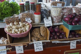 Various dried fruits, onions and nuts in jars on a market stall with price tags, market hall,