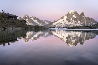 Evening mood with pink evening sky, mountain landscape with mountain hut Refuge du Lac Blanc at