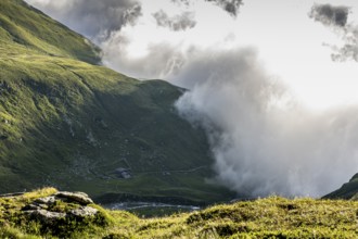 Dramatic mountain landscape with low-hanging clouds and green valleys, alpine hut, Neukirchen am