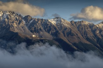 Majestic snow-covered mountain peaks in the morning light, surrounded by clouds and soft rays of