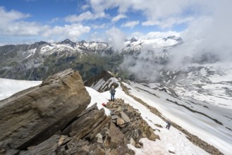 Mountaineer on a rocky ridge with snow, descent from the summit of Schönbichler Horn, view of