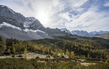 Mountain panorama with steep rocky peaks, yellow-coloured larches in autumn, hike to the summit of