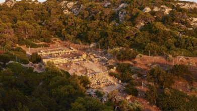 The warm rays of the sun illuminate an ancient ruins site in a hilly landscape, Heraion of