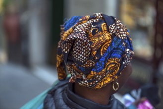 Colourful turban of a black immigrant woman in the old town of Genoa, Italy, Europe