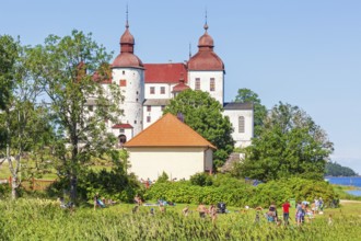 Läckö castle a famous Swedish baroque castle with people sunbathing at the bathing place on a sunny