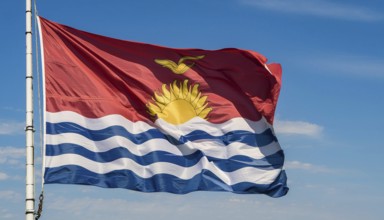 The flag of Kiribati, Polynesia, flutters in the wind, isolated against a blue sky