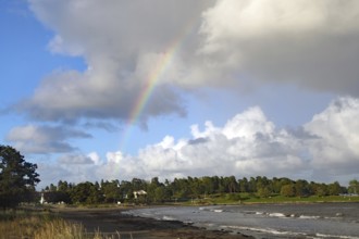 View of the coastal landscape with a rainbow over wooded area under a partly cloudy sky, Tönsberg,