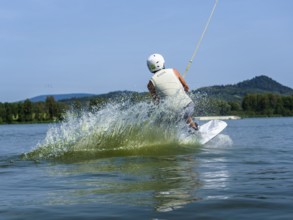 Young man jumping with wakeboard into the lake, water sports, water skiing in wakepark, Stráž pod