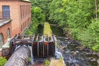 Old hydroelectric plant still in use at a rapid river in a lush deciduous forest, Ryfors, Mullsjö,