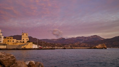 Romantic picture of the coast at dawn, with historic buildings on the shore and mountainous