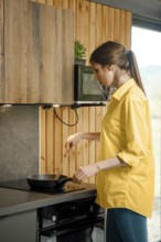 Woman cooking cooking scrambled eggs, stirring eggs in a pan with spatula