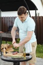 Man cooking steak for outdoor barbecue. He sprinkling fresh meat with pepper