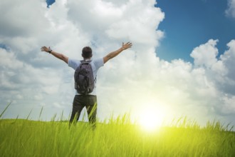 A backpacker on a hill with blue sky and copy space, man backpacking on a green hill with copy