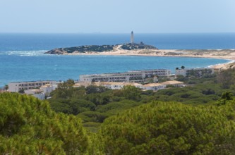 Island with lighthouse and white buildings, surrounded by green forest and blue sea, view of Los