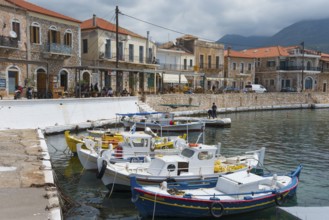 Small harbour with fishing boats in front of a row of traditional stone buildings on the coast with