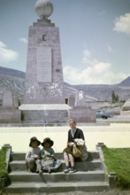 Tourist with local children at the equator monument from 1936, Ciudad Mitad del Mundo, Pichincha,