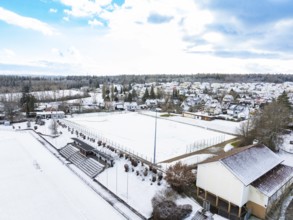 Snow-covered sports field with surrounding houses and buildings in a wintry environment, Calw-