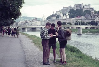 Two hitchhikers being helped with directions by a man, Salzach River riverbank, Salzburg, Austria