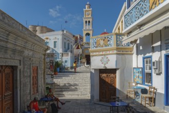 Lively street scene of picturesque Olymbos village with traditional architecture and a clock in