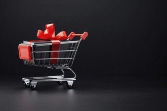 Shopping cart with gift box with red robbon on black backrgound with copy space. KI generiert,