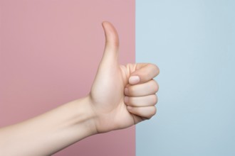 Woman's hand showing positive thumbs up sign in front of pastel pink and blue background. KI