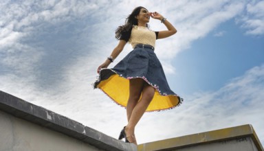 Woman in a dress with yellow lining posing on a roof in front of a cloudy sky, AI generated, AI