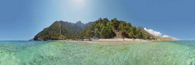 Panoramic view of the idyllic Apella beach with green vegetation and clear turquoise water under a