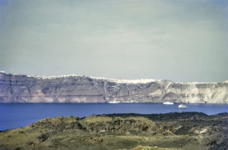 View of whitewashed clifftop buildings of Fira from Nea Komeni volcanic park, Santorini, Cyclades