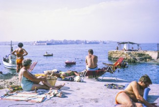 People sunbathing on rocky coastal ledge by Mediterranean Sea, Syracuse, Sicily, Italy, Europe