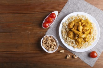 Rice with chicken curry sauce with cashew on brown wooden background. top view, copy space