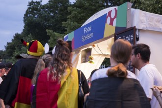 Fans with German flags in front of one of the food stalls in the fan zone at the Brandenburg Tor