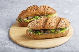 Sprats sandwiches with lettuce and cream cheese on wooden board on a gray concrete background. side