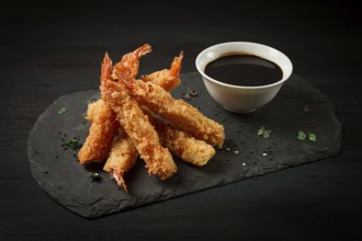 Shrimp in tempura, deep-fried, on black slate, with soy sauce, horizontal, no people