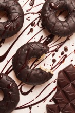 Donuts, in chocolate glaze, on a beige background, with liquid chocolate