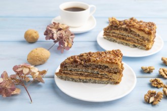 Walnut and hazelnut cake with caramel cream, cup of coffee on blue wooden background. side view,