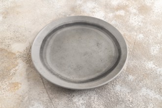 Empty gray ceramic plate on gray concrete background. Side view, copy space