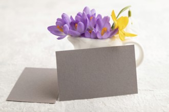 Gray paper business card mockup with spring snowdrop crocus and galanthus flowers on gray concrete